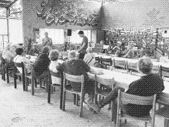 Atelier philo sous la halle du tiers-lieu Le Lien, participants assis autour de longues tables.